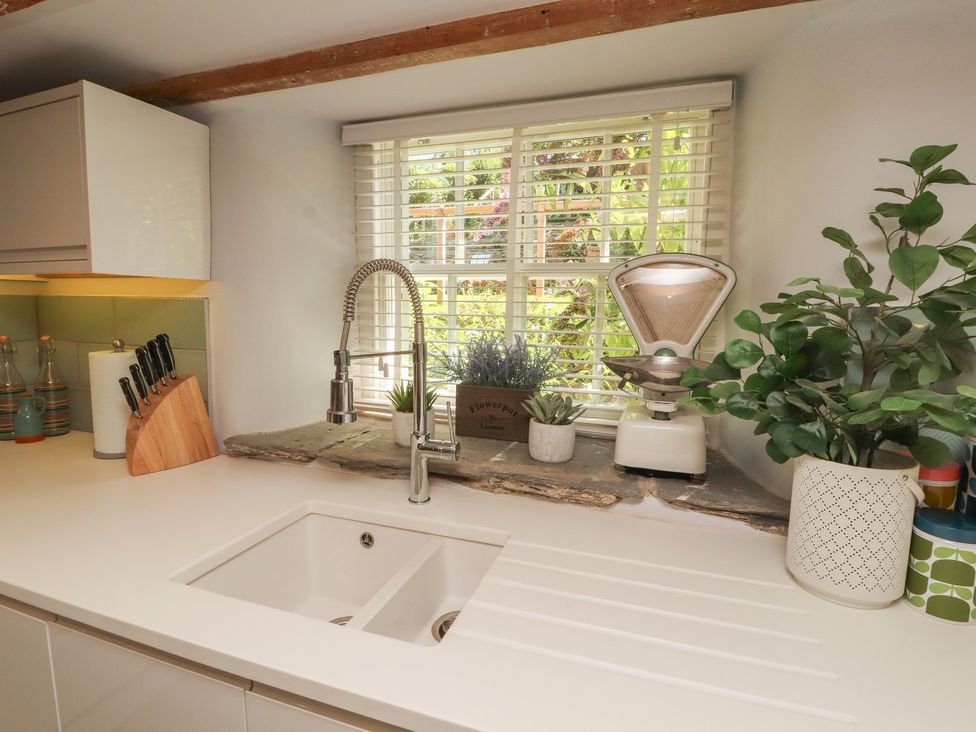 A kitchen with a sink and plants on the countertop at Haws Bank Cottage in Coniston