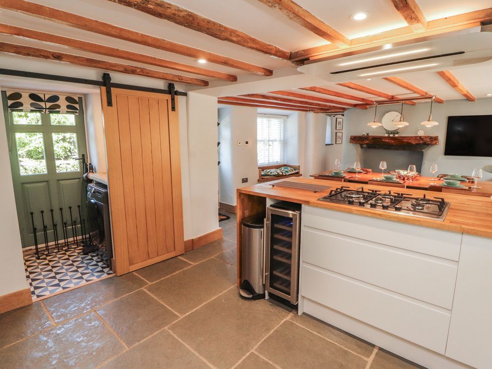 A kitchen with a stove, wine cooler, and countertop at Haws Bank Cottage in Coniston