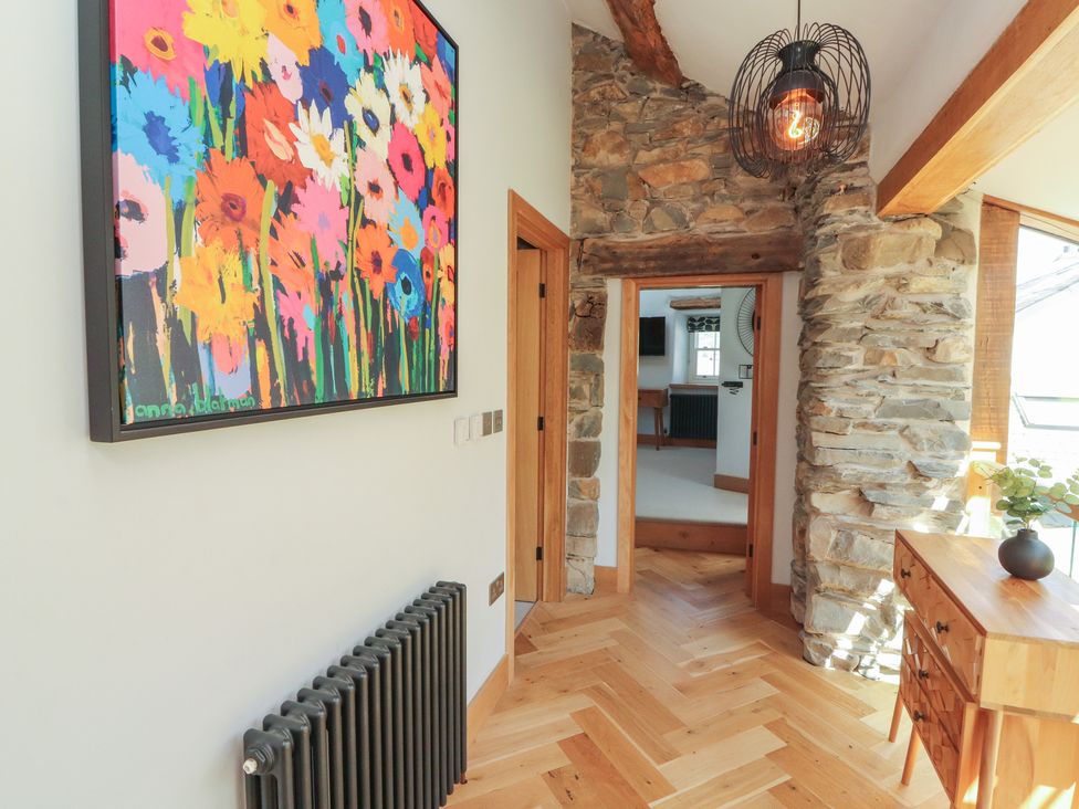A hallway with a painting and wooden table at Haws Bank Cottage Coniston
