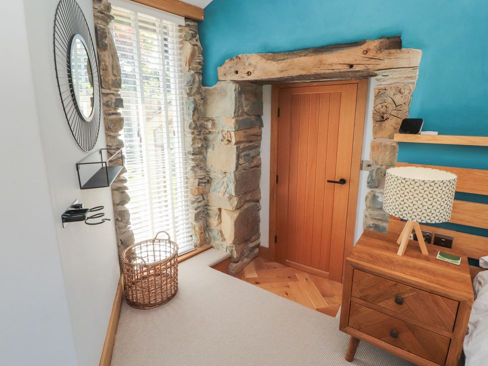 A bedroom with a door and bedside table at Haws Bank Cottage in Coniston