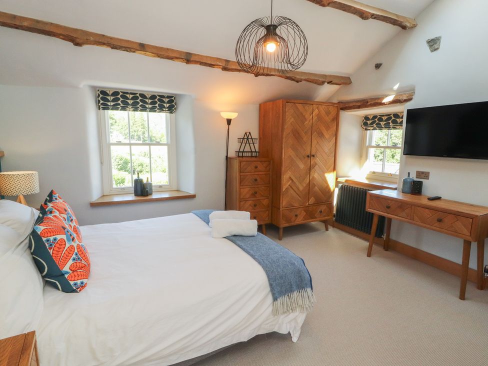 A bedroom with a bed and wardrobe at Haws Bank Cottage in Coniston