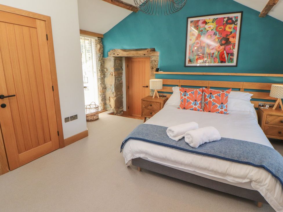 A bedroom with a bed and artwork at Haws Bank Cottage in Coniston