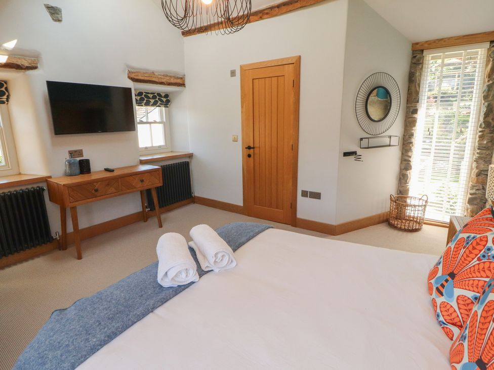 A bedroom with a bed and television at Haws Bank Cottage in Coniston