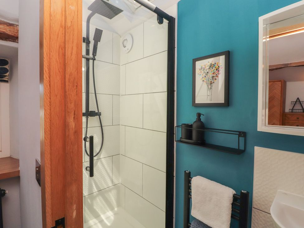 A bathroom with a shower and towel rack at Haws Bank Cottage in Coniston