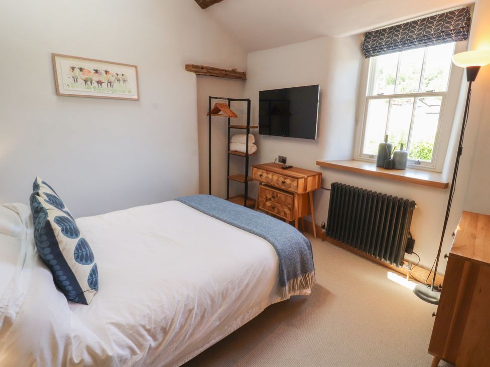 A bedroom with a bed and television at Haws Bank Cottage in Coniston