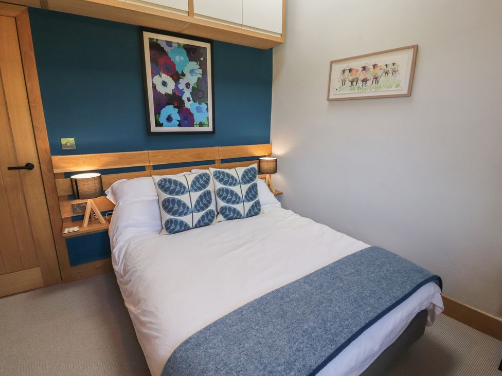 A bedroom with a bed and wall art at Haws Bank Cottage in Coniston