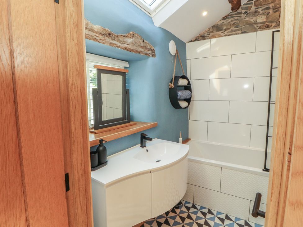 A bathroom with a tub and sink at Haws Bank Cottage in Coniston