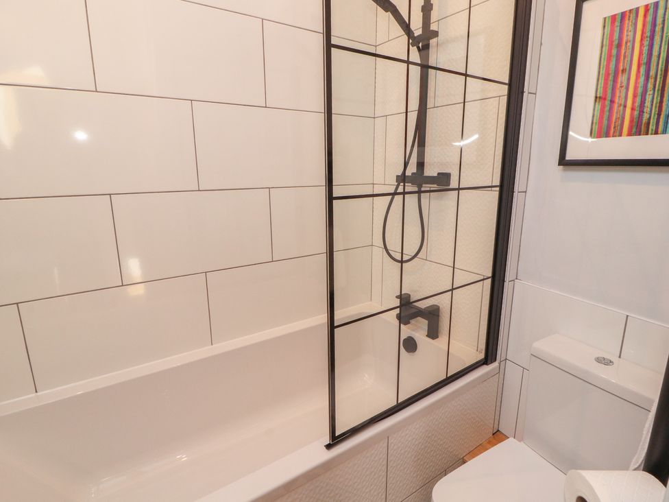 A bathroom with a bathtub and shower at Haws Bank Cottage in Coniston