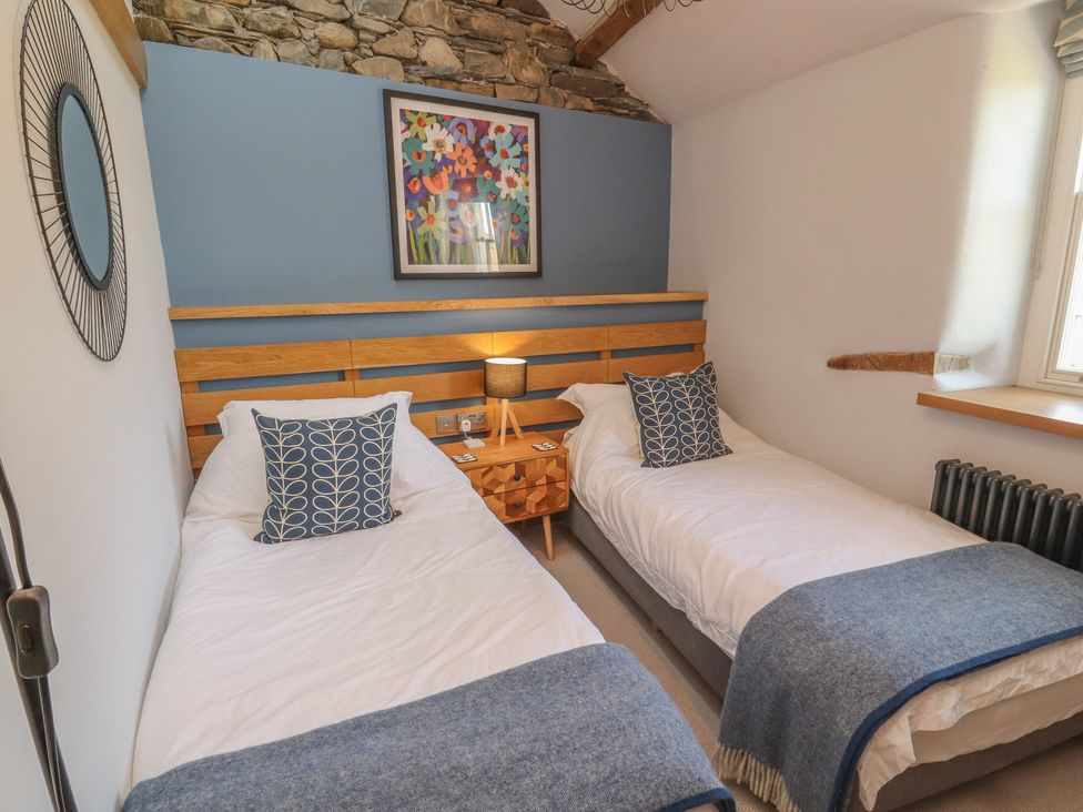 A bedroom with two single beds and artwork at Haws Bank Cottage in Coniston