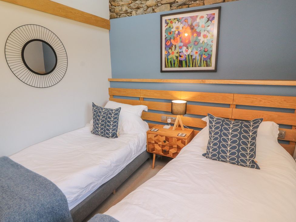 A bedroom with twin beds and a bedside table at Haws Bank Cottage in Coniston