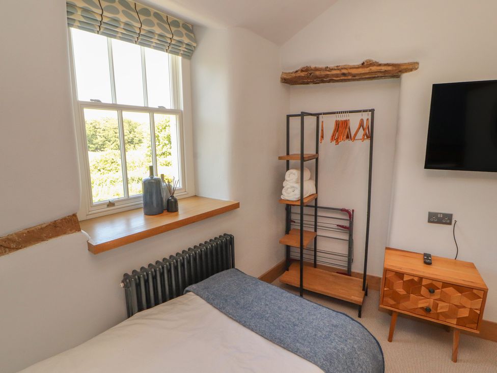 A bedroom with a window, clothes rack, and television at Haws Bank Cottage in Coniston