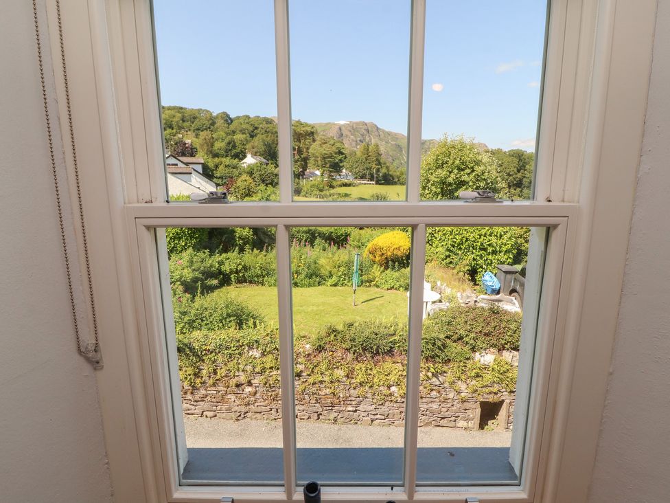 A view of a garden and mountains from a window at Haws Bank Cottage in Coniston