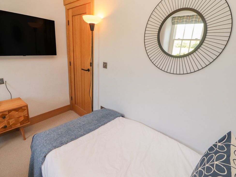 A bedroom with a bed and television at Haws Bank Cottage in Coniston