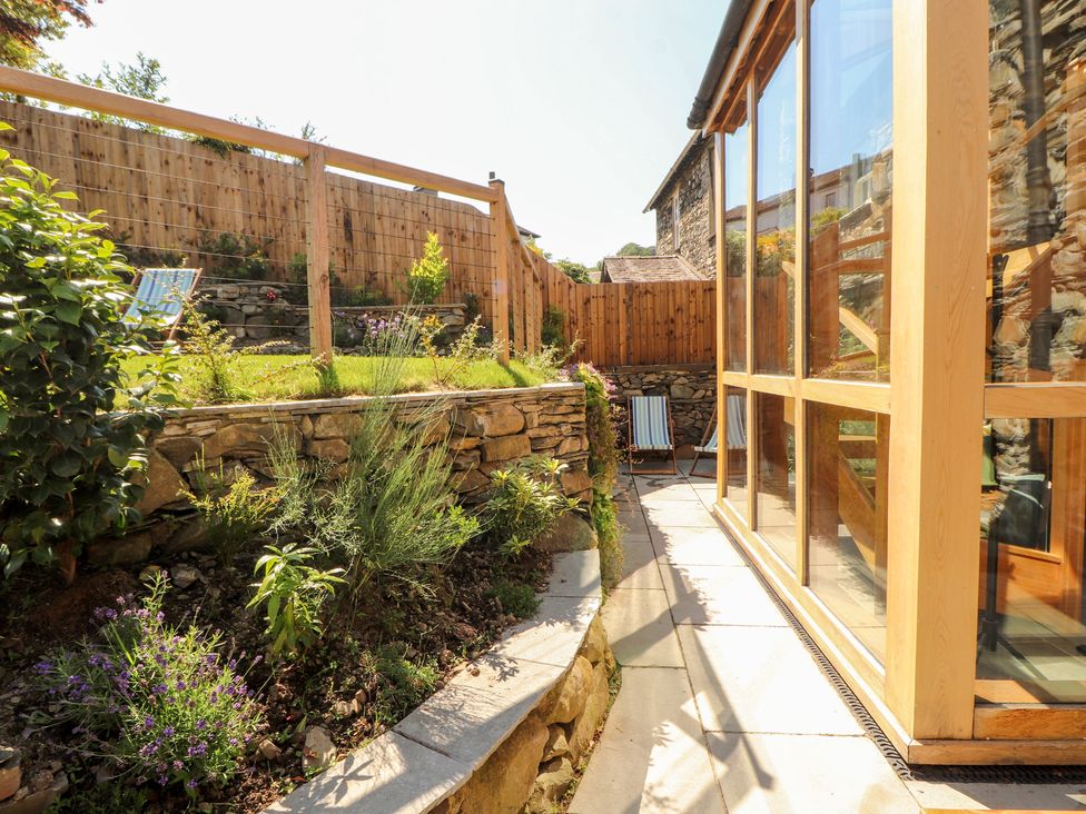 A garden with plants and a glass structure at Haws Bank Cottage in Coniston