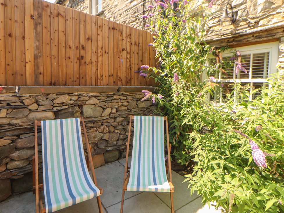 A garden with deck chairs and flowers at Haws Bank Cottage in Coniston