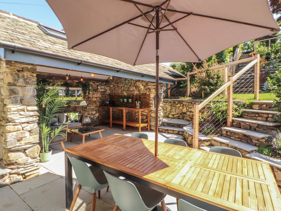An outdoor dining area with a table and umbrella at Haws Bank Cottage in Coniston
