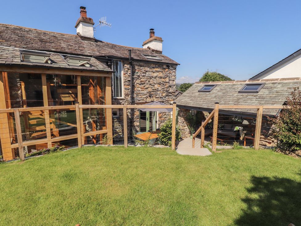 A garden with a wooden fence and stone wall at Haws Bank Cottage in Coniston