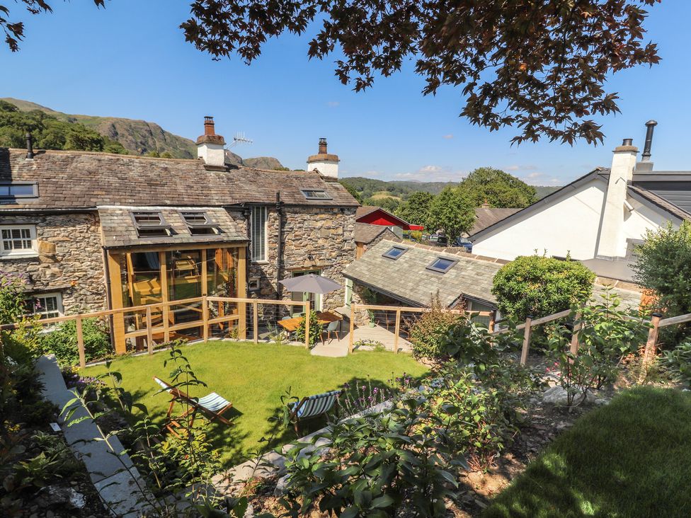 A garden with lawn and wooden structures at Haws Bank Cottage in Coniston