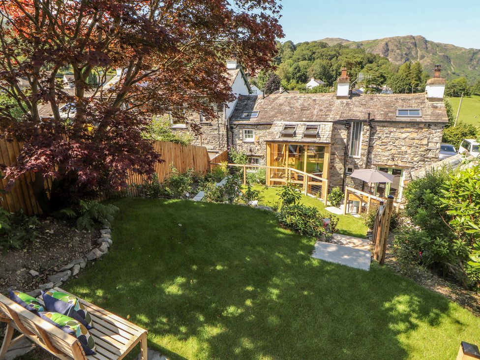 A garden with a tree and a house at Haws Bank Cottage in Coniston