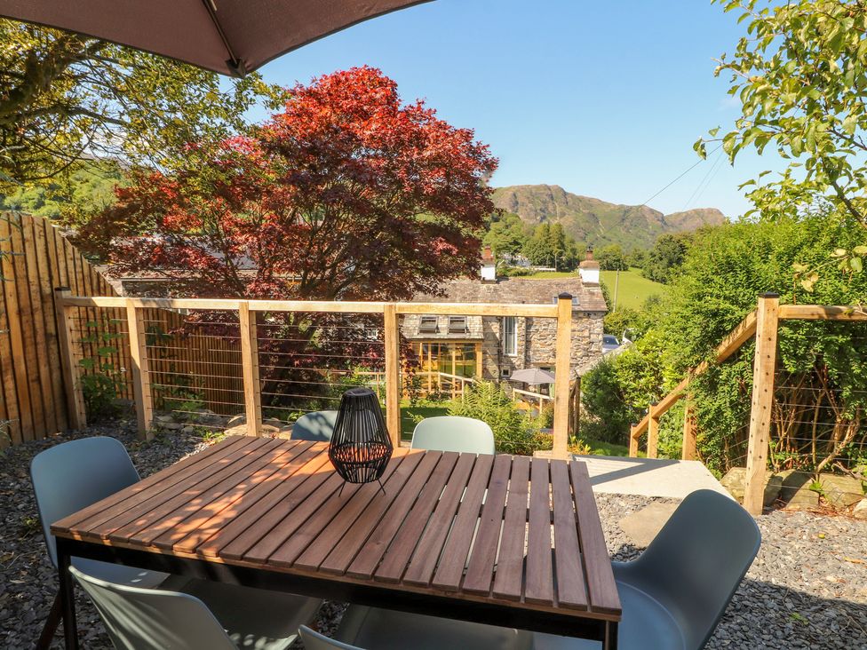 A garden with a wooden table and chairs at Haws Bank Cottage in Coniston