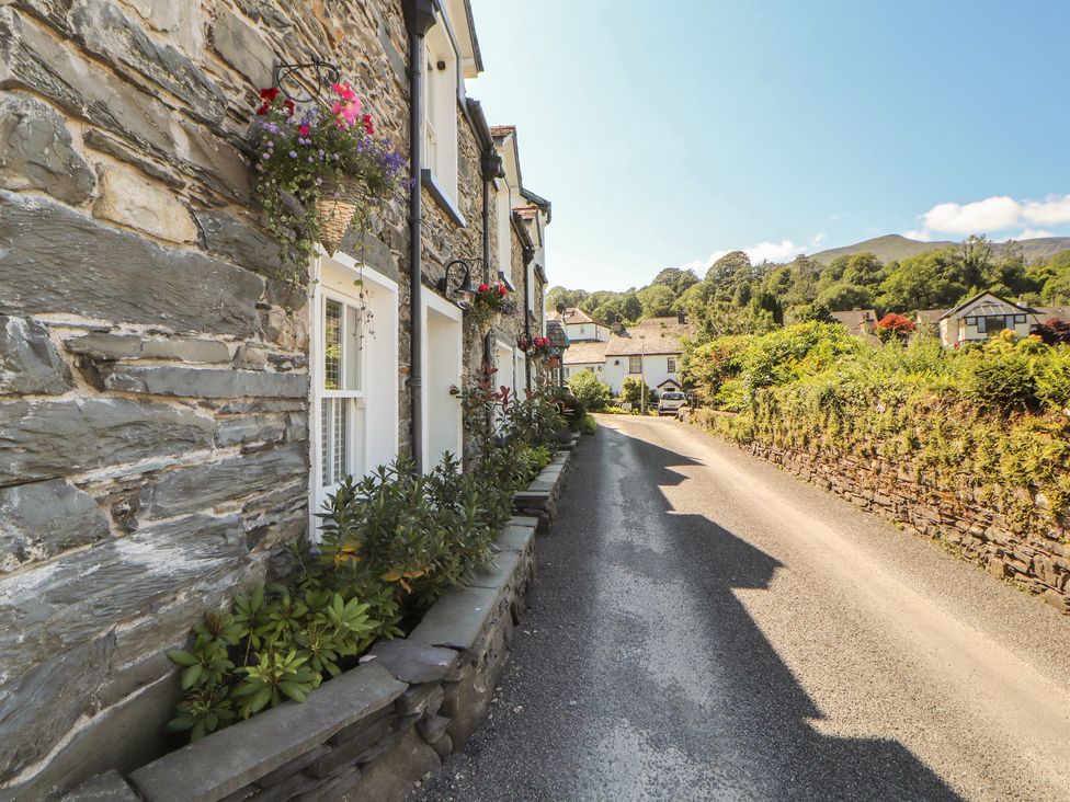 A street view with stone houses and greenery at Haws Bank Cottage in Coniston