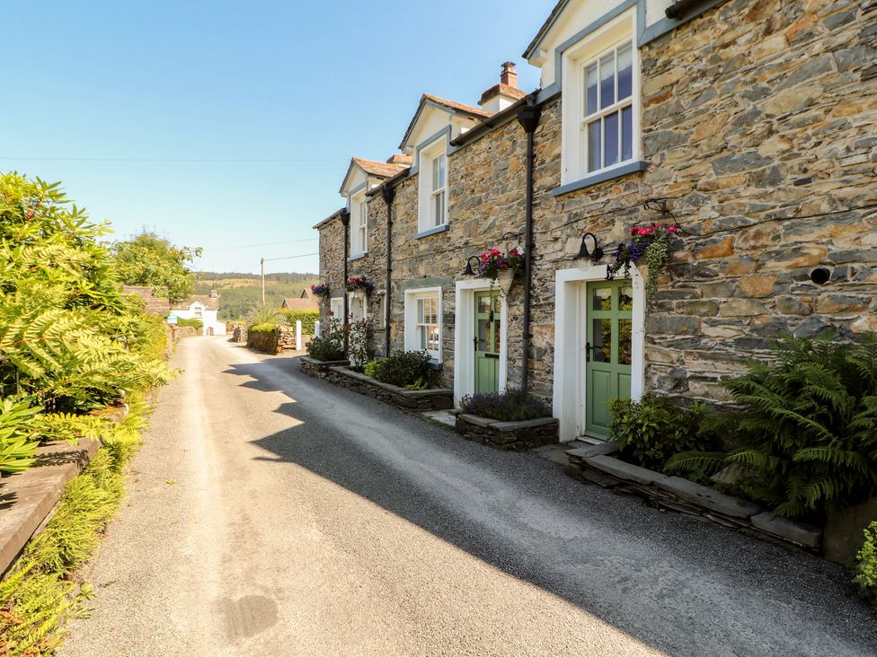 Stone cottages with greenery along the road at Haws Bank Cottage in Coniston