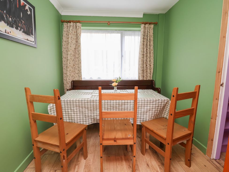 A dining room with a table and wooden chairs at Hafan Deg in Holywell