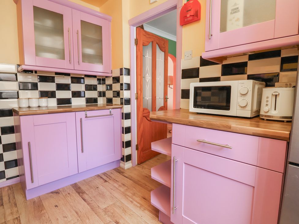A kitchen with pink cabinets and appliances at Hafan Deg in Holywell