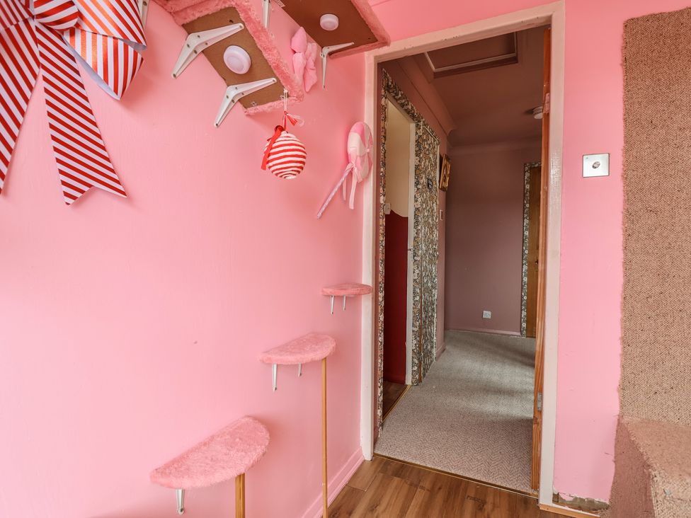 A hallway with pink walls and a staircase at Hafan Deg in Holywell