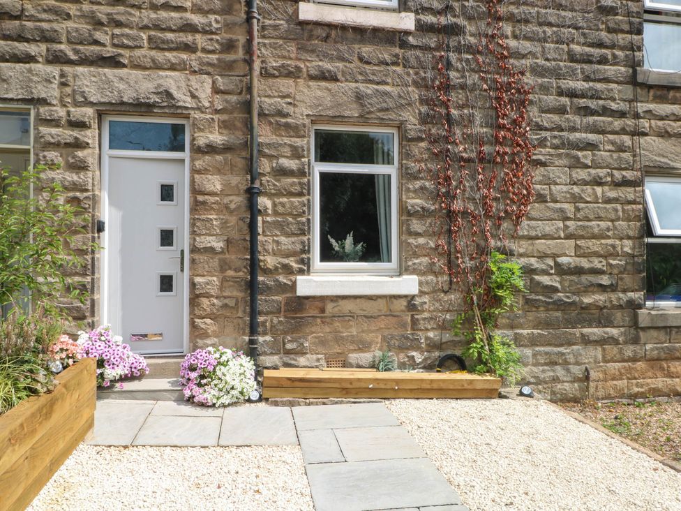 A front entrance with a door and window beside a floral garden at 2 Bentley Bridge Cottages Matlock