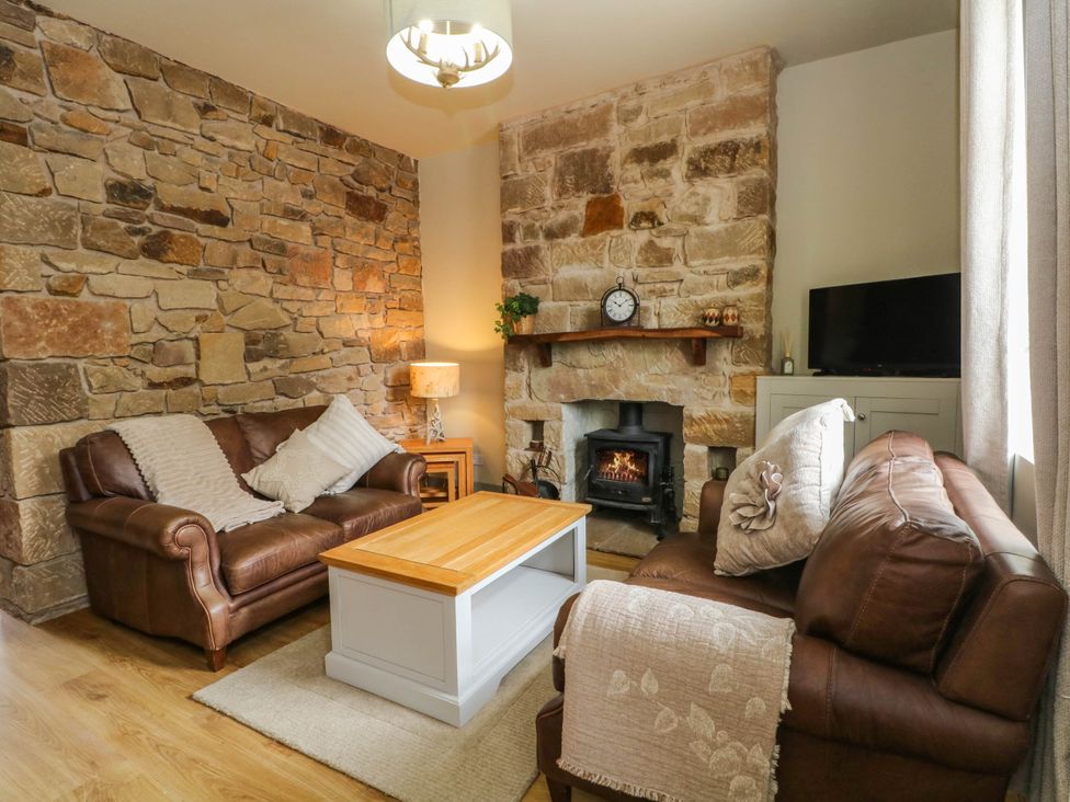 A living room with a sofa and fireplace at 2 Bentley Bridge Cottages Matlock