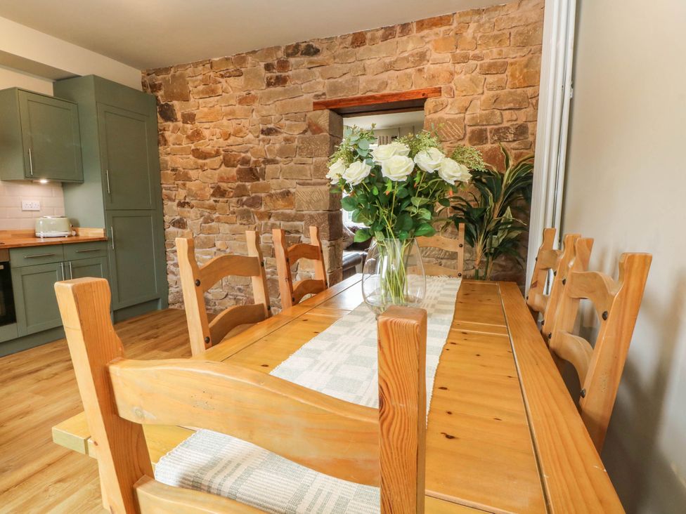 A dining room with a wooden table and chairs at 2 Bentley Bridge Cottages in Matlock