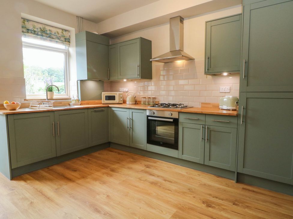 A kitchen with green cabinets and countertop at 2 Bentley Bridge Cottages in Matlock