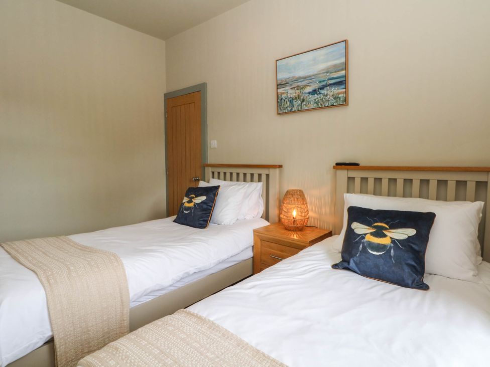 A bedroom with two beds and a nightstand at 2 Bentley Bridge Cottages in Matlock
