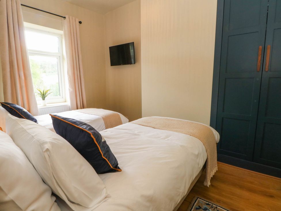 A bedroom with two beds and a television at 2 Bentley Bridge Cottages in Matlock
