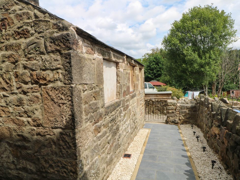 An outdoor area with a stone wall and a paved pathway at 2 Bentley Bridge Cottages Matlock