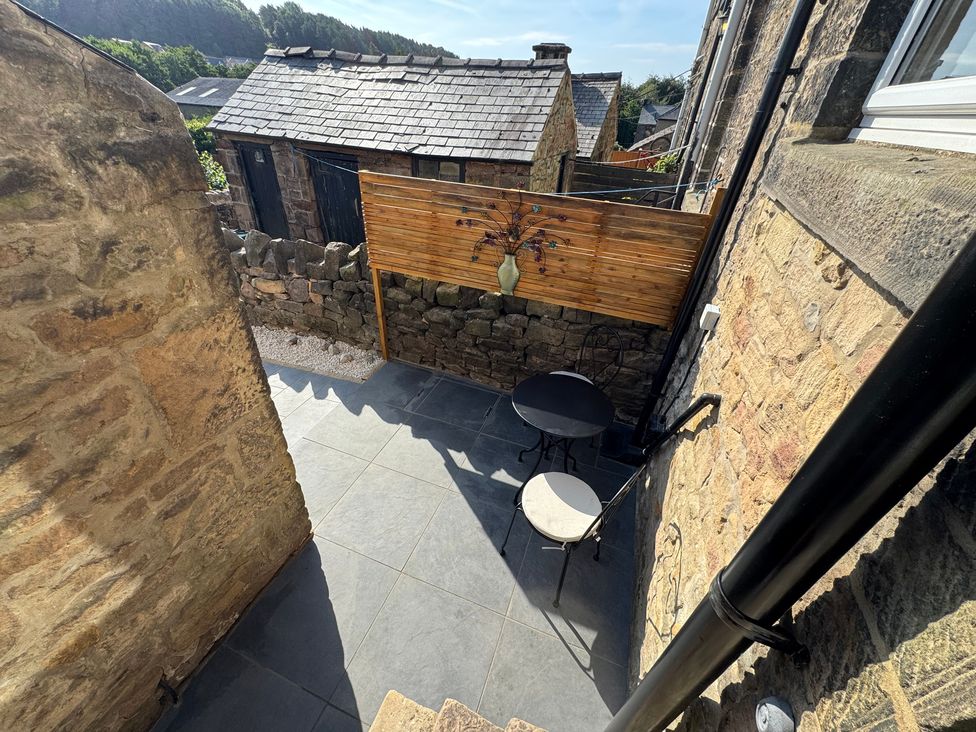 An outdoor area with a table and chair near a stone wall at 2 Bentley Bridge Cottages Matlock