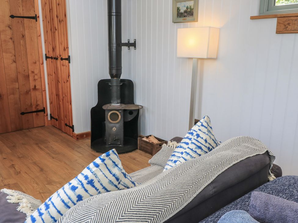 A living room with a stove and a lamp at Damsons in Williton