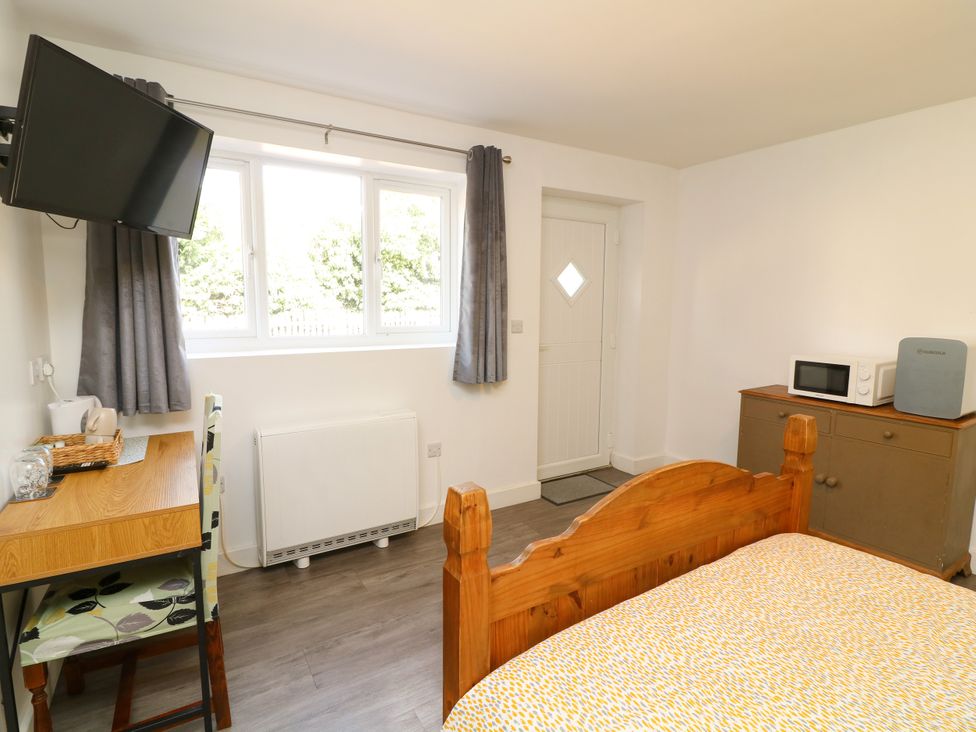 A bedroom with a bed, desk, microwave, and television at Walcott Lodges - Kirkstead in Billinghay, Lincolnshire