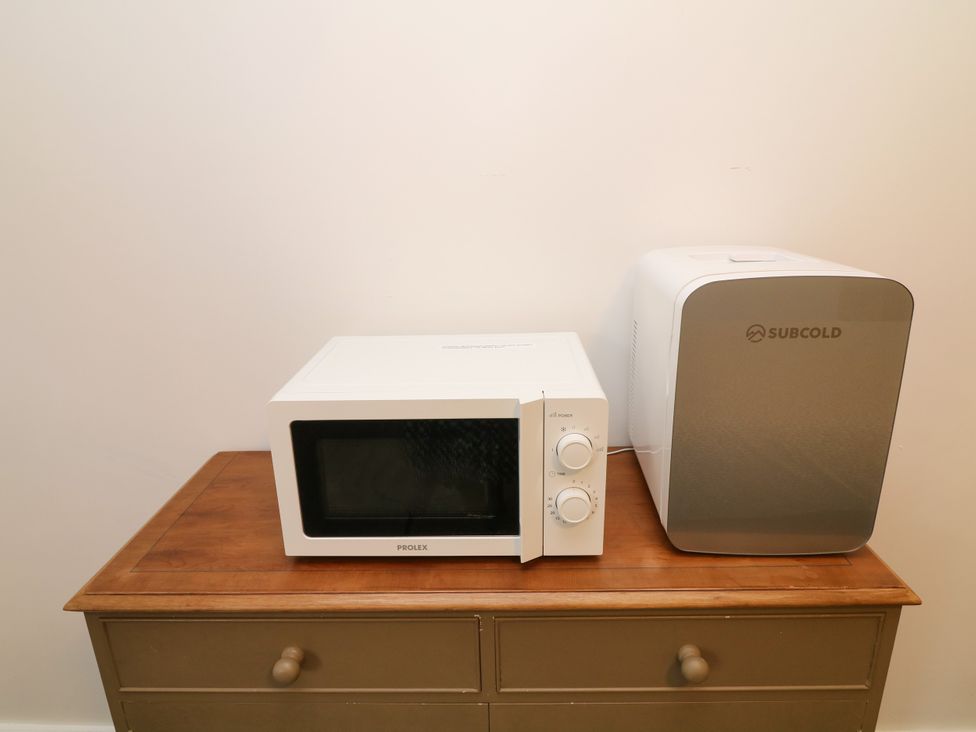 A microwave and mini fridge on a wooden cabinet at Walcott Lodges - Kirkstead in Billinghay, Lincolnshire