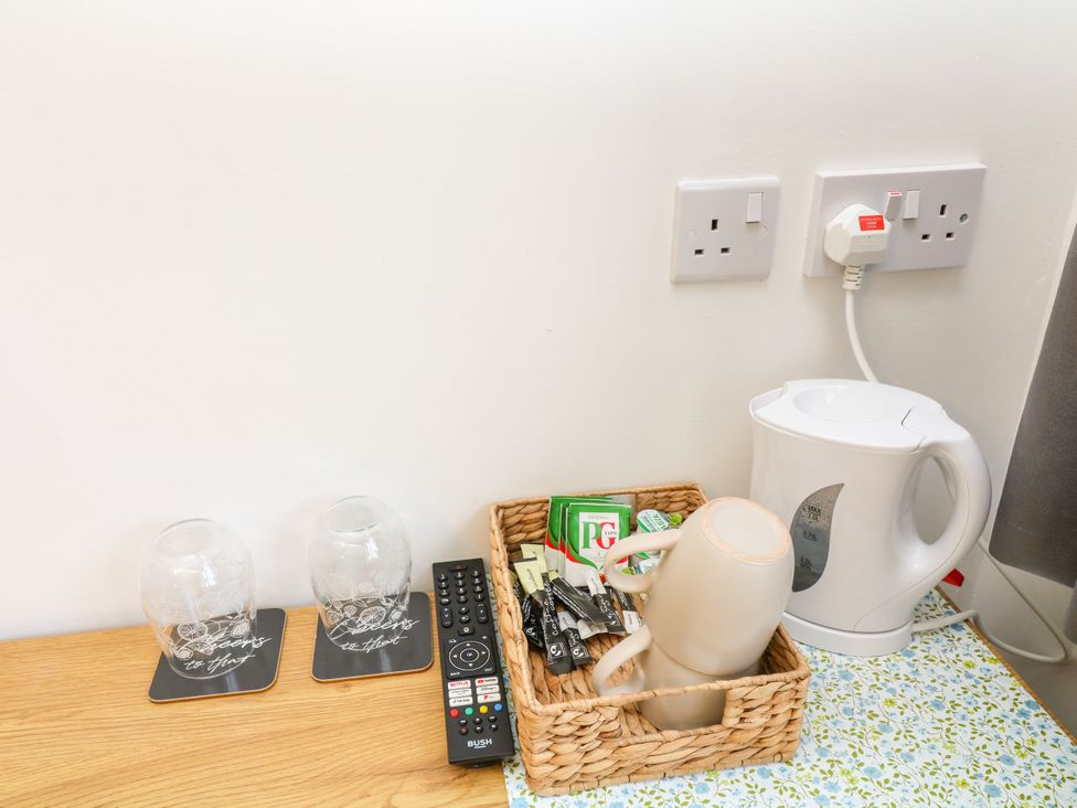 A kettle and basket with mugs and tea bags in the kitchen at Walcott Lodges - Kirkstead, Billinghay, Lincolnshire