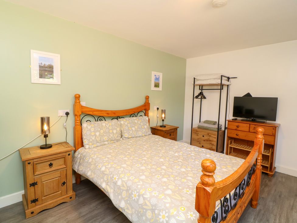 A bedroom with a wooden bed and furniture at Walcott Lodges - Barlings in Billinghay, Lincolnshire