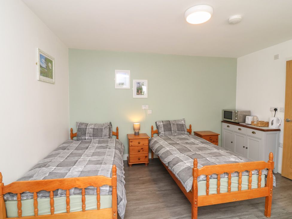A bedroom with two single beds and a kitchenette at Tupholme in Billinghay, Lincolnshire