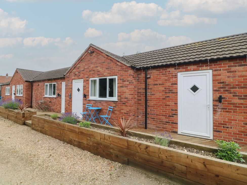 An outdoor area with brick houses and blue chairs at Tupholme in Billinghay, Lincolnshire