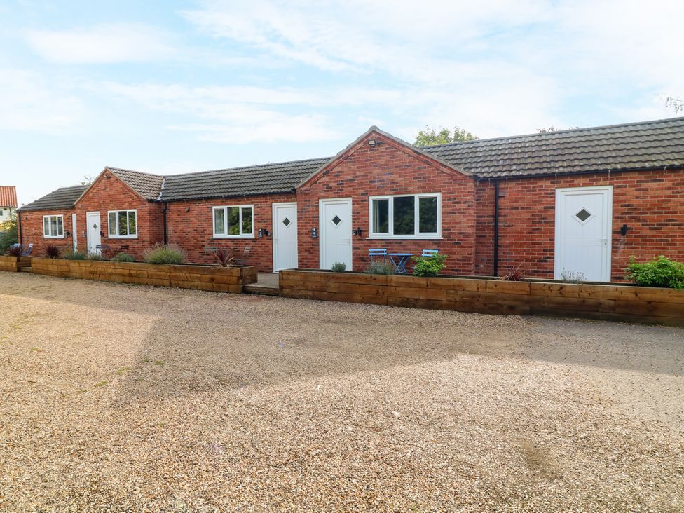 Exterior view of brick buildings with white doors and a gravel area at Walcott Lodges - Tupholme in Billinghay, Lincolnshire