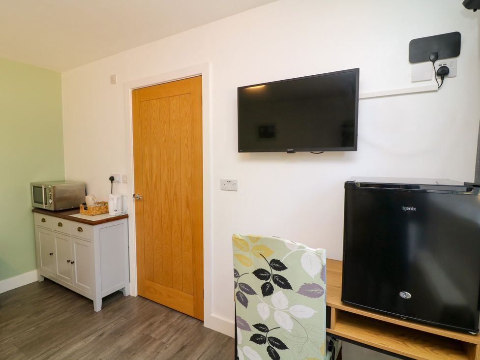 A kitchen with a microwave, television, and fridge at Walcott Lodges - Tupholme, Billinghay, Lincolnshire