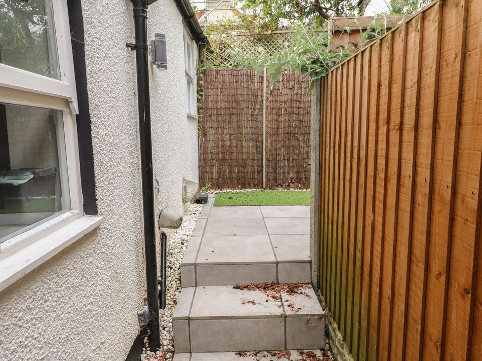 A pathway leading to grass area with wooden fence at Conway Mart Cottage in Conwy
