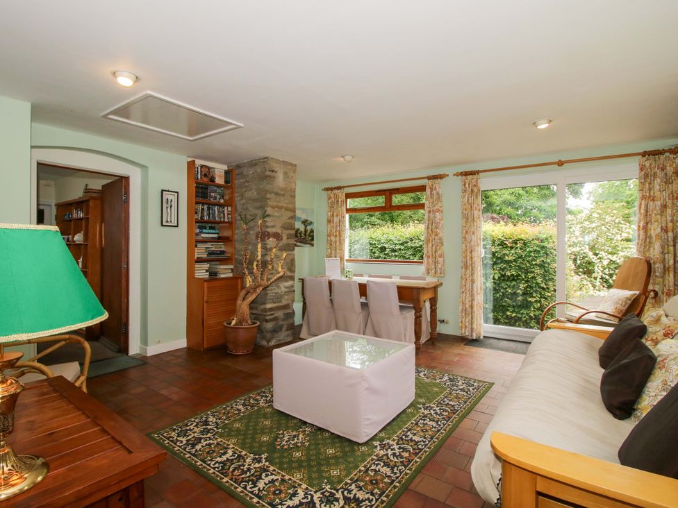 A living room with a sofa, table, and bookshelf at Kwerky Cottage