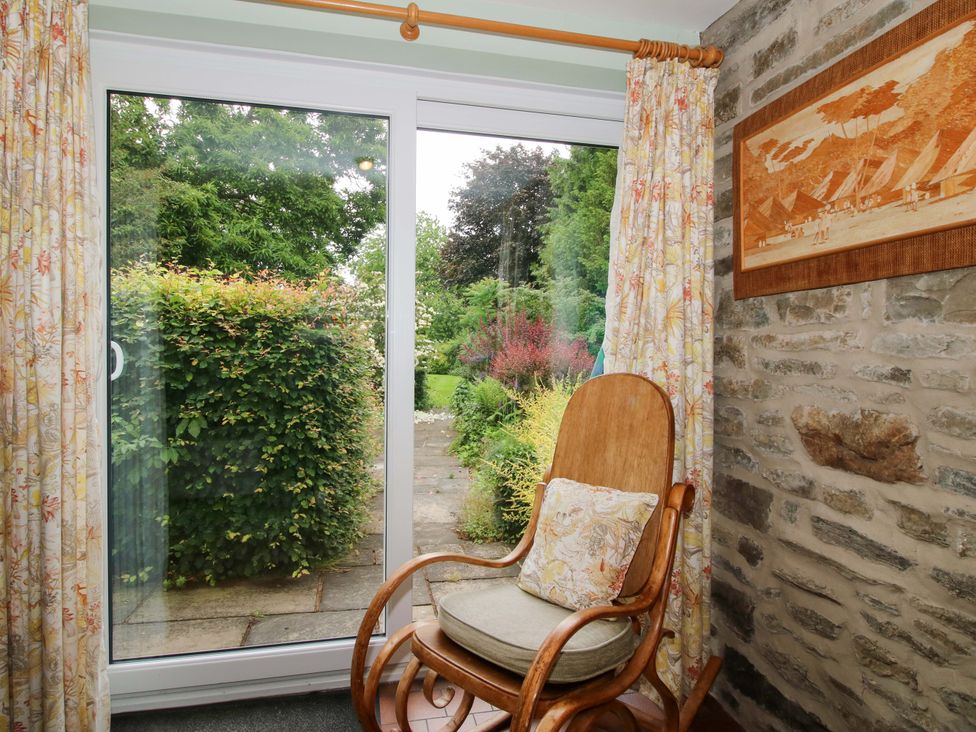 A seating area with a sliding glass door and garden view at Kwerky Cottage