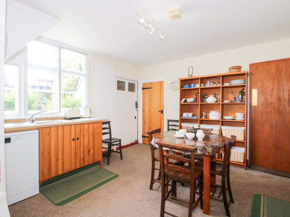 A kitchen with a dining table and shelving unit at Kwerky Cottage